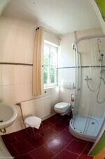Helles Badezimmer mit Dusche, Toilette, Waschbecken und Fenster im Sandgut Mihla Gasthof und Hotel.