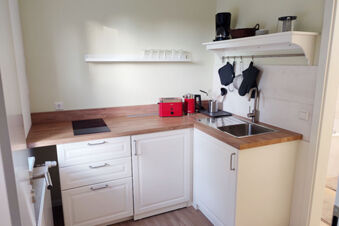 Helle und moderne Kitchenette mit Holzarbeitsplatte und roten Ger&auml;ten im Sandgut Mihla Gasthof und Hotel, sauber und funktional