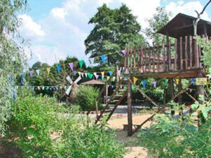 Outdoor playground area at Hotel Zu den Schildb&uuml;rgern with wooden structures, colorful pennant flags, and greenery surrounding it
