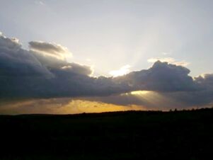 Sunset sky with large dark clouds and a hint of sun rays above a flat landscape near Hotel Zu den Schildb&uuml;rgern