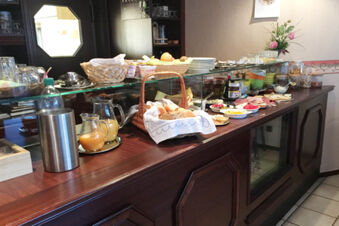 Breakfast buffet with drinks, bread, plates, fruits, spreads, and cereals on a wooden counter at Pension Haus Wiehenperle