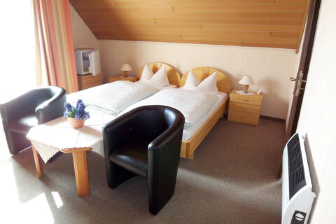 Pension Haus Wiehenperle room with two single beds, wooden furniture, two black chairs, and a small table with flowers