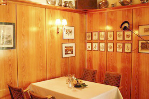 Wood panelled corner dining area with decorated chairs and table set with flowers at Hotel Restaurant Illemann
