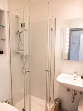 Helles Badezimmer mit Duschkabine und Waschbecken im JU 52 Hotel Arnsberg, modern und funktional eingerichtet.