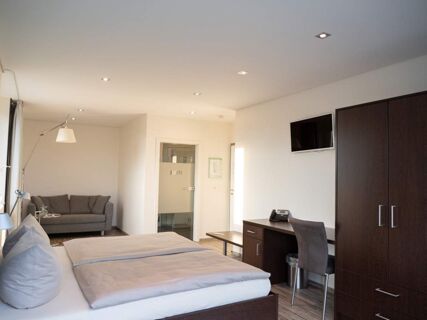 Modern eingerichtetes Hotelzimmer mit Doppelbett, Sofa, Schreibtisch und TV im JU 52 Hotel Arnsberg f&uuml;r komfortable &Uuml;bernachtungen.