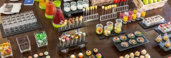 A variety of colorful desserts, fresh fruit jars, juice pitchers, small glasses, and snacks arranged for breakfast at NH Hotel M&uuml;nchen Dornach