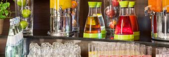 Collection of glass bottles, glasses, juice dispensers with fruit-infused beverages at NH Hotel M&uuml;nchen Dornach breakfast area