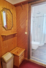 &Scaron;alia įėjimo į pensiono "Zur Elbe" modernų vonios kambarį su du&scaron;u ir tualetu įrengtas medinėmis dailylentėmis apkaltas kampas su veidrodžiu ir lentyna.