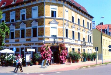 Istorinis pensiono "Zur Elbe" pastatas su daugybe gėlių prie&scaron;ais įėjimą ir lauko sėdimomis vietomis saulės atokaitoje.