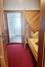 Nedidelio vie&scaron;bučio kambario koridorius su raudonu kilimu, medinėmis dailylentėmis, viengulė lova ir vonios kambariu Pension Zur Elbe.