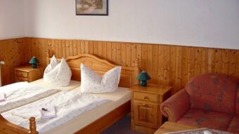 Jaukus dvivietis kambarys su mediniais baldais, dviem lovomis ir raudonu foteliu ramioje ir draugi&scaron;koje vietoje įsikūrusiame pensione "Zur Elbe".