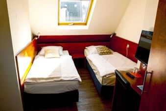Kleines Doppelzimmer mit zwei Einzelbetten unter einem Dachfenster im Hotel Haus Rheinblick, ausgestattet mit Schreibtisch und TV.
