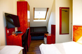 Helles Hotelzimmer mit roten M&ouml;beln, Doppelbett und Fenster im Dachgeschoss im Hotel Haus Rheinblick, gem&uuml;tlicher Arbeitsplatz vorhanden.