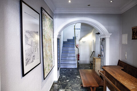 Eingangsbereich mit Treppe und Sitzbank im Hotel Haus Rheinblick, mit Landkartenbildern an der Wand und Marmorfu&szlig;boden.