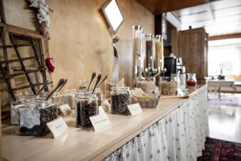 Buffet mit verschiedenen M&uuml;slisorten und Trockenfr&uuml;chten im hellen Fr&uuml;hst&uuml;cksraum des Hotel Engel mit rustikalem Holzdesign.