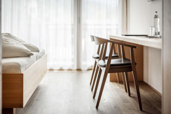 Modern eingerichtetes Hotelzimmer mit zwei Holzst&uuml;hlen, einem schlichten Bett und einem hellen Fenster im Hotel Engel.