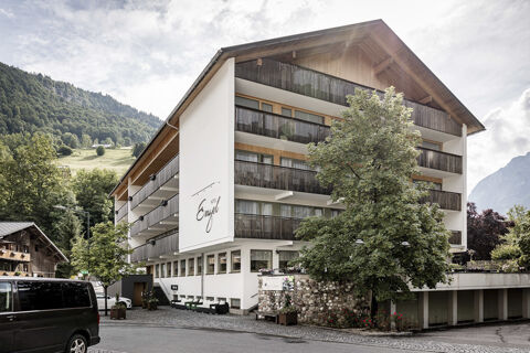 Das Hotel Engel zeigt seine moderne Fassade mit Balkonen und begr&uuml;ntem Au&szlig;enbereich in einer malerischen Berglandschaft.