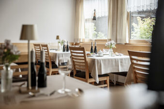 Helles und gem&uuml;tliches Restaurant mit Holzm&ouml;beln und gedeckten Tischen im Hotel Engel, dekoriert mit Blumen und Weinflaschen.