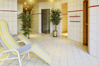 Entspannungsbereich mit bequemen Liegest&uuml;hlen und gr&uuml;nen Pflanzen in einem gefliesten Raum des Hotel Engel Spa-Bereichs.