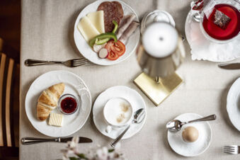Fr&uuml;hst&uuml;ckstisch mit Croissant, Marmelade, Eierbecher, K&auml;se, Wurst und Tee im Hotel Engel, elegant gedeckt mit wei&szlig;em Geschirr.
