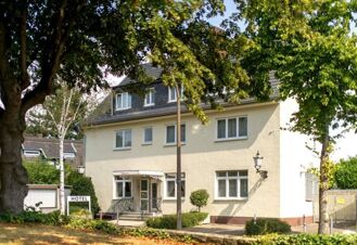 Die Fassade von Hotel Dieck zeigt ein helles Geb&auml;ude mit mehreren Fenstern und einem Eingangsbereich in einem gr&uuml;nen, von B&auml;umen umgebenen Umfeld.