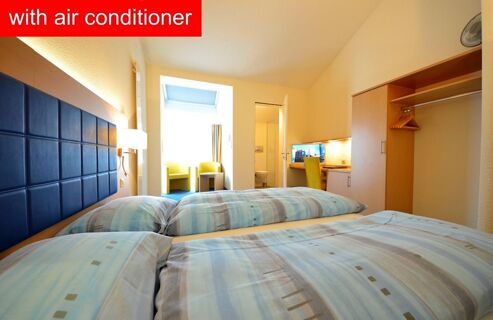 Hotel-Restaurant Felmis Nichtraucherhaus room with twin beds, blue headboard, desk, chairs, open closet, and window light