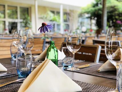 Eleganter gedeckter Tisch mit Weingl&auml;sern, blauer Vase und Servietten im Hotel-Restaurant Felmis Nichtraucherhaus, gem&uuml;tliches Ambiente.