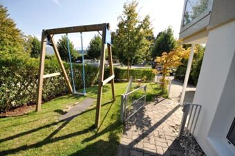 Au&szlig;enbereich mit Schaukel und gepflegtem Garten, umgeben von B&auml;umen, im Hotel-Restaurant Felmis Nichtraucherhaus