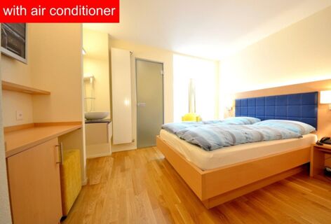 Hotel-Restaurant Felmis Nichtraucherhaus room with wooden floor, double bed with blue headboard, small sink, and yellow chair by window