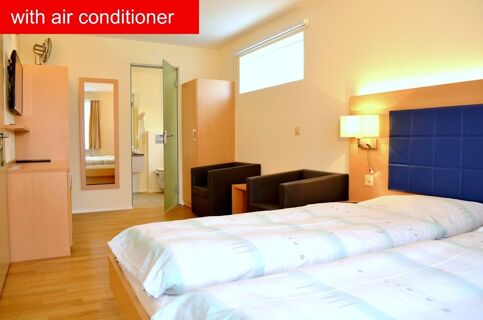 Hotel-Restaurant Felmis Nichtraucherhaus room with two single beds, blue headboard, two black armchairs, and wooden furniture including a mirror and wardrobe