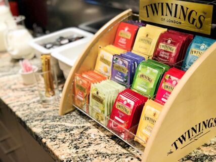 Tea packets of various flavors labeled Twinings displayed in a wooden holder on a granite countertop at Hotel-Restaurant Felmis Nichtraucherhaus