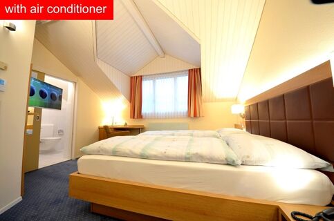 Hotel-Restaurant Felmis Nichtraucherhaus bedroom with double bed, blue carpet, desk, chair, window, and bathroom with wall-mounted TV