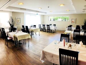 Modern eingerichteter Speisesaal mit wei&szlig;en Tischdecken und Kerzen im Hotel-Restaurant Felmis Nichtraucherhaus f&uuml;r angenehme Stunden.