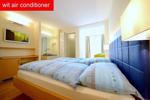 Hotel-Restaurant Felmis Nichtraucherhaus room with double bed, blue padded headboard, wooden furniture, and a window with curtains