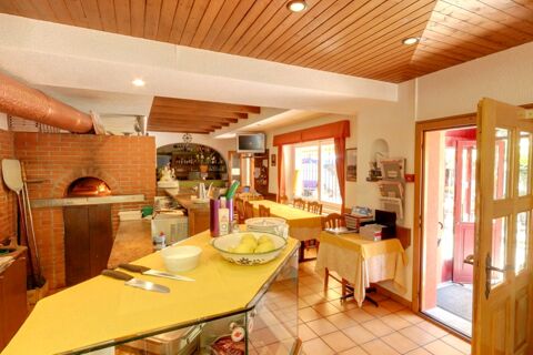 Interior view of Ristorante Albergo Grotto Serta showing a brick pizza oven, tables with yellow tablecloths, and an open door
