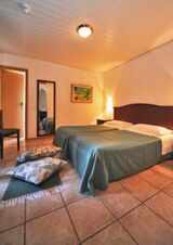 Hangulatos sz&aacute;llodai szoba francia&aacute;ggyal, t&uuml;k&ouml;rrel, sz&eacute;kkel &eacute;s dekor&aacute;ci&oacute;val a Ristorante Albergo Grotto Serta &eacute;tteremben, melegen megvil&aacute;g&iacute;tott &eacute;s h&iacute;vogat&oacute;.