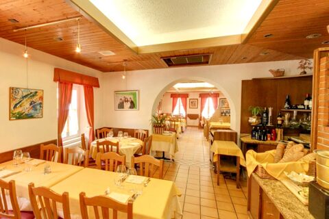 Dining area with wooden chairs and yellow tablecloths inside Ristorante Albergo Grotto Serta with bread basket on counter