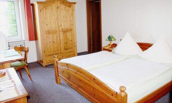 Gem&uuml;tlich eingerichtetes Doppelzimmer mit Holzm&ouml;beln und gro&szlig;em Bett im Hotel Pension Haus Hahnenbecke f&uuml;r komfortablen Aufenthalt.