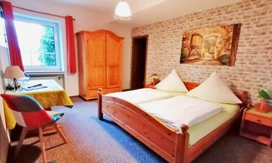 Gem&uuml;tliches Hotelzimmer mit Doppelbett, Holzm&ouml;beln und Fenster in Hotel Pension Haus Hahnenbecke, passend f&uuml;r erholsame N&auml;chte.
