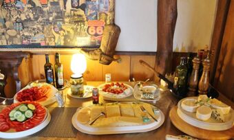 Buffet mit verschiedenen K&auml;sesorten, frischem Gem&uuml;se und Weinen in rustikalem Ambiente von Hotel Pension Haus Hahnenbecke.