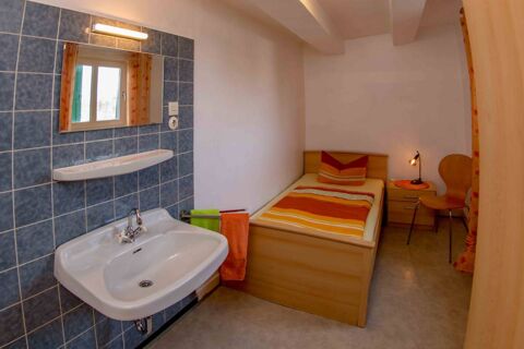 Kleines Zimmer mit Einzelbett, Waschbecken und Spiegel, schlicht eingerichtet im Lindensch&auml;nke Hotel garni f&uuml;r G&auml;stekomfort.