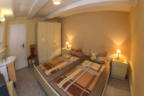 Kompaktes und gem&uuml;tliches Schlafzimmer mit zwei Einzelbetten, Nachttischlampen und einem Schrank im Lindensch&auml;nke Hotel garni.