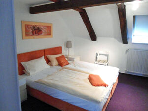 Gem&uuml;tliches Schlafzimmer im Hotel-G&auml;stehaus Br&uuml;ggemann mit Doppelbett, Dachschr&auml;ge und stimmungsvoller Beleuchtung.