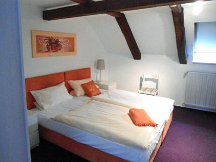 Gem&uuml;tliches Schlafzimmer im Hotel-G&auml;stehaus Br&uuml;ggemann mit Doppelbett, Dachschr&auml;ge und stimmungsvoller Beleuchtung.