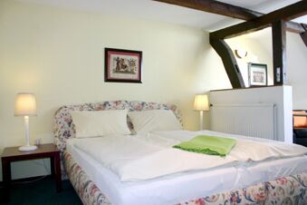 Gem&uuml;tliches Doppelbett mit gemustertem Kopfteil, zwei Nachttischen und Lampen im Zimmer vom Hotel-G&auml;stehaus Br&uuml;ggemann.
