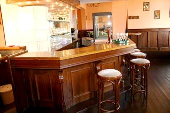 Die klassische Bar mit Holztheke und hohen Hockern im Hotel-G&auml;stehaus Br&uuml;ggemann l&auml;dt zum Verweilen in gem&uuml;tlicher Atmosph&auml;re ein.