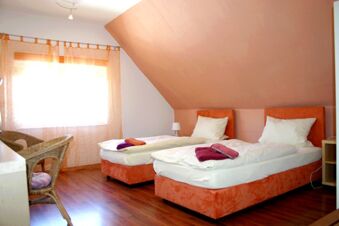 Helles Zimmer mit zwei Einzelbetten und Holzfu&szlig;boden im Hotel-G&auml;stehaus Br&uuml;ggemann, freundliche Einrichtung mit Fenster und Korbst&uuml;hlen.