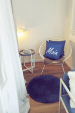 Gem&uuml;tliche Sitzecke mit Stuhl, blauem Kissen und Beistelltisch im Zimmer des Landhotel Alte M&uuml;hle, hell und einladend gestaltet.