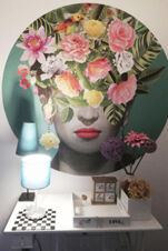 Kunstvolles Wandbild mit Blumen und einem Gesicht &uuml;ber einem Tisch mit Dekoration im Landhotel Alte M&uuml;hle, modernes und kreatives Interieur.
