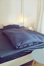 Schlichtes und modernes G&auml;stezimmer im Landhotel Alte M&uuml;hle mit dunkelblauer Bettw&auml;sche und hellem Ambiente.